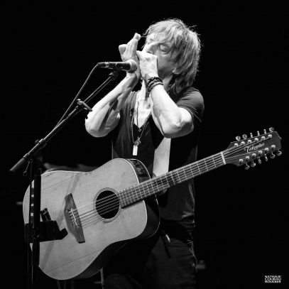 Portrait de Jean-Louis Aubert harmonica et guitare 12 cordes