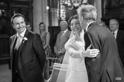 Mariage en l'église Saint-Germain-l'Auxerrois à Paris. Le papa de la mariée l'embrasse en arrivant à l'autel - photographe Nathalie Courau-Roudier