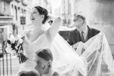 Mariée qui retient son voile à son arrivée à l'église Notre-Dame de Lorette à Paris - photographe Nathalie Courau Roudier