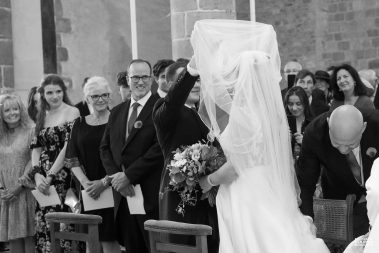 Photo de mariage : le marié remonte le voile de la mariée dans l'église - Photographe Nathalie Courau-Roudier