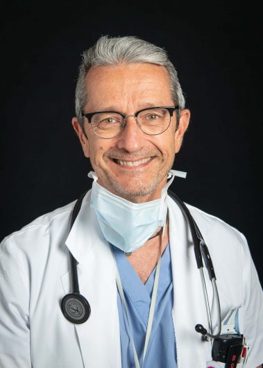 Portrait pro corporate d'un médecin en tenue de bloc sur fond noir