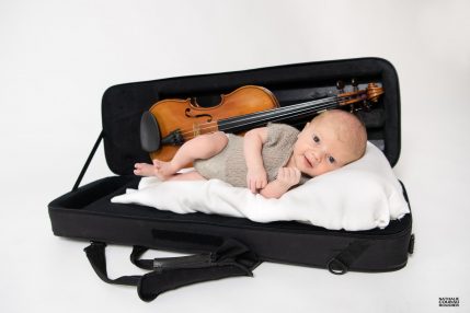 Séance photo studio Naissance le bébé couché dans l'étui de violon de sa maman