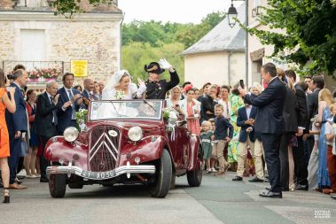 Les mariés quittent l'église dans une voiture de collection - Photographe Nathalie Courau-Roudier