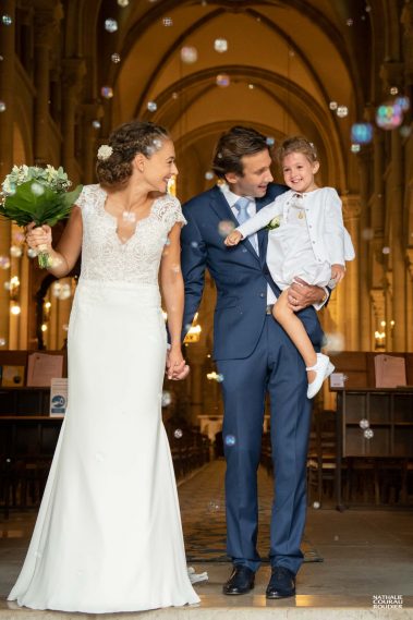 Messe de mariage en l'église Saint-Pierre de Neuilly sur Seine : les mariés sortent avec leur fille sous les bulles de savon - Photographe Nathalie Courau-Roudier