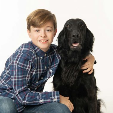 Portrait studio d'un chien Flat Coated noir et son jeune maître