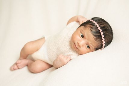 Photo studio Naissance, nouveau-né sur une couverture rose pâle avec un petit serre-tête en croquet rose