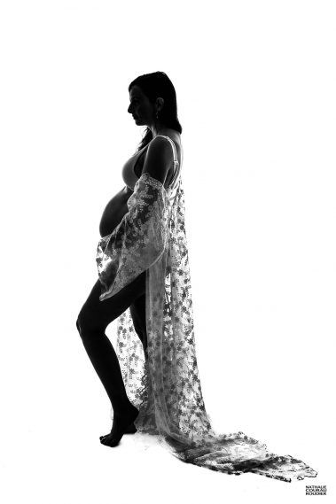 photo studio de grossesse femme enceinte avec un peignoir de dentelle en contre-jour