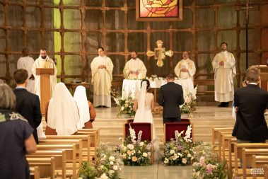 Pendant leur messe de mariage, les mariés de dos et les prêtres - Photographe Nathalie Courau-Roudier